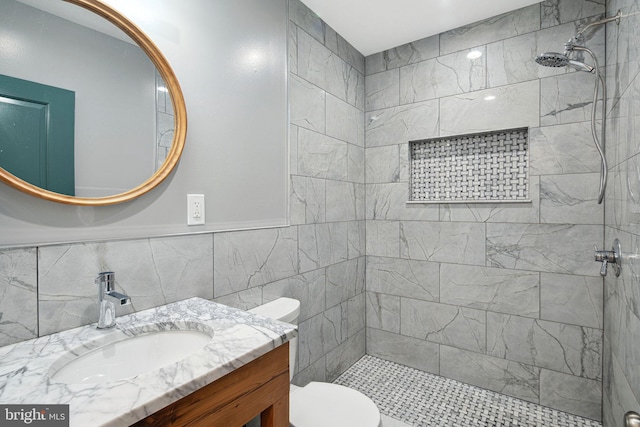 bathroom featuring vanity, toilet, tile walls, and a shower stall