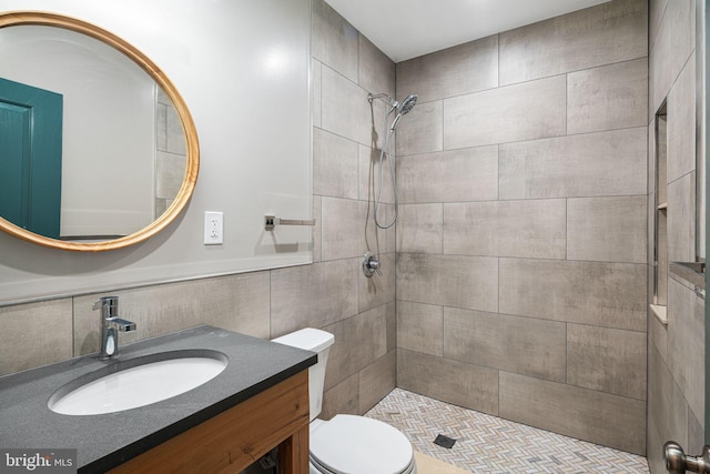 full bath featuring vanity, tiled shower, tile walls, toilet, and tasteful backsplash