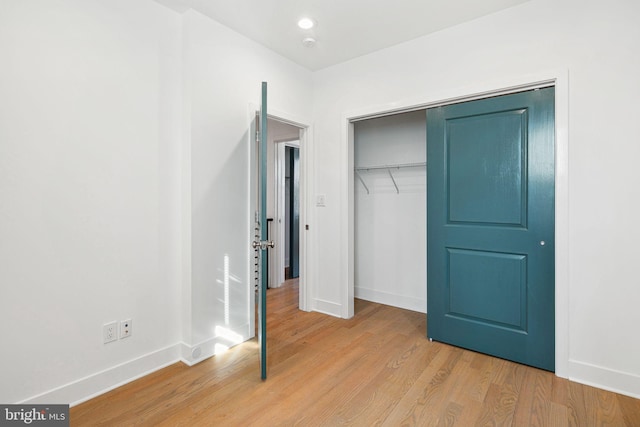 unfurnished bedroom with recessed lighting, light wood-type flooring, baseboards, and a closet