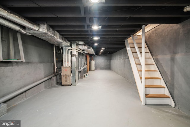 unfinished basement featuring stairway, heating unit, and water heater