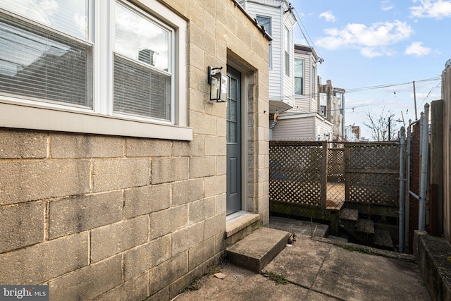 view of side of home with entry steps, concrete block siding, and fence