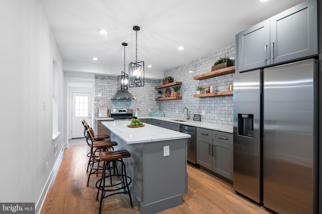 kitchen with open shelves, light wood-style flooring, gray cabinetry, a sink, and appliances with stainless steel finishes