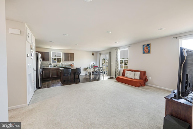 living room featuring recessed lighting, baseboards, and dark colored carpet