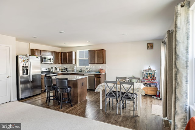 kitchen featuring a breakfast bar, dark wood-type flooring, appliances with stainless steel finishes, and a center island