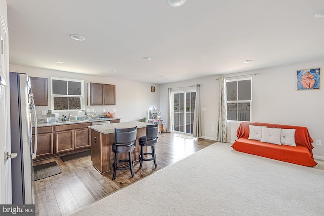 kitchen featuring a sink, a kitchen breakfast bar, a center island, freestanding refrigerator, and light wood finished floors