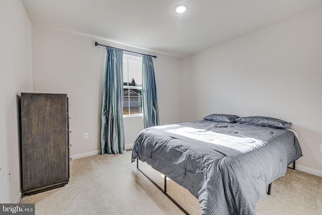 bedroom with baseboards and light colored carpet