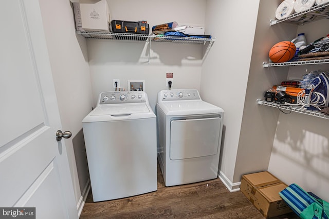 clothes washing area with washer and dryer, baseboards, wood finished floors, and laundry area