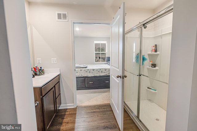 ensuite bathroom featuring vanity, wood finished floors, visible vents, a stall shower, and ensuite bathroom