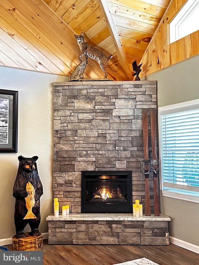 room details featuring beam ceiling, wood finished floors, a stone fireplace, baseboards, and wood ceiling