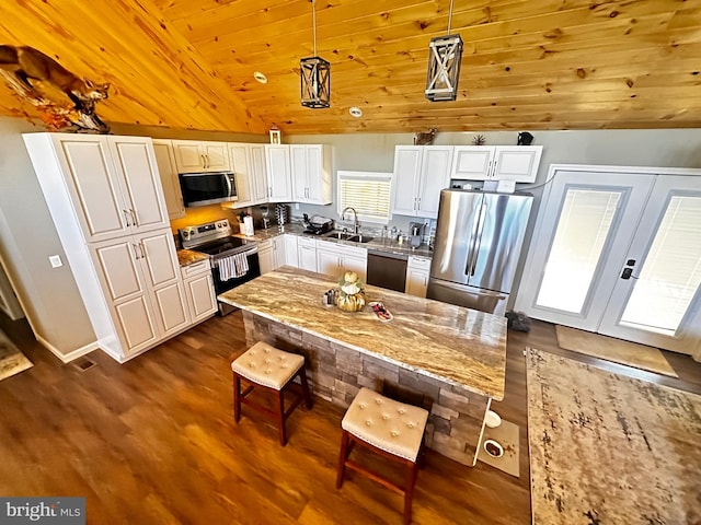 kitchen featuring dark wood finished floors, a sink, stainless steel appliances, vaulted ceiling, and white cabinetry