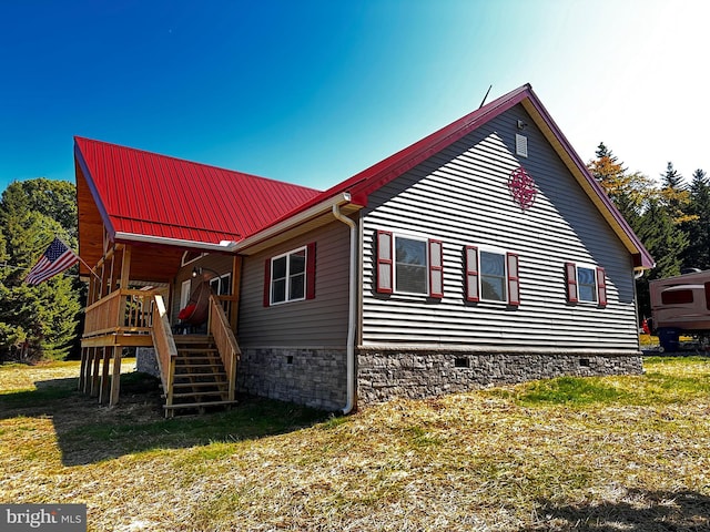 view of home's exterior featuring stairway, a yard, metal roof, and crawl space