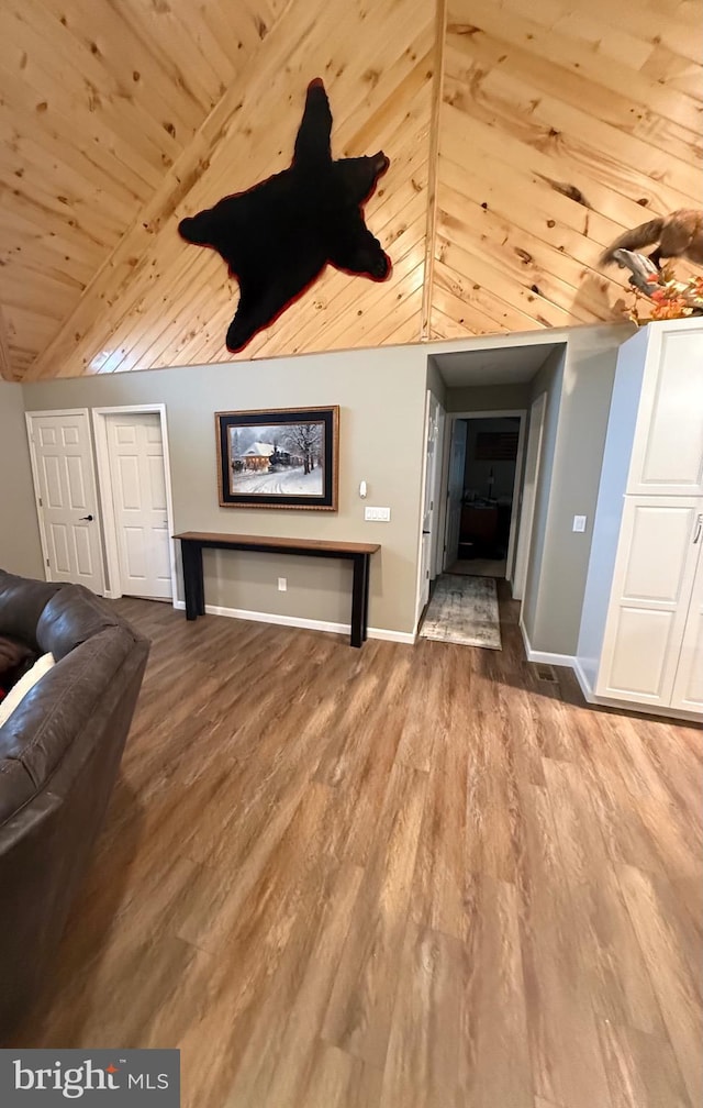 unfurnished living room with vaulted ceiling, wooden ceiling, baseboards, and wood finished floors