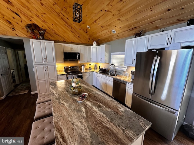 kitchen with dark wood-style flooring, a sink, vaulted ceiling, white cabinets, and appliances with stainless steel finishes