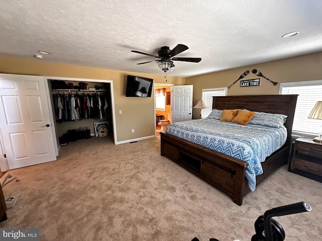 carpeted bedroom featuring a closet, multiple windows, a textured ceiling, and a ceiling fan