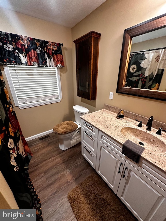 bathroom featuring vanity, wood finished floors, visible vents, a textured ceiling, and toilet