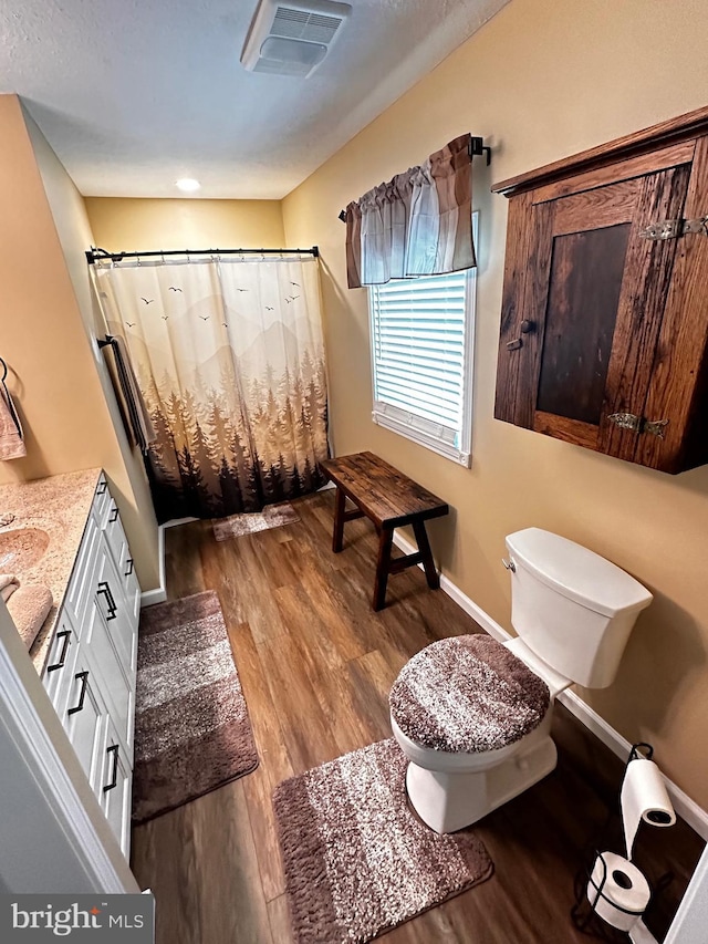 bathroom with wood finished floors, visible vents, baseboards, curtained shower, and toilet