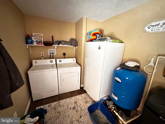 washroom featuring washer and dryer, wood finished floors, and laundry area