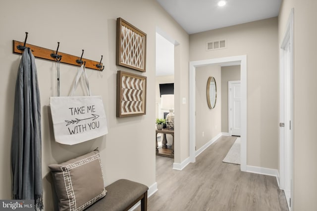 hall featuring visible vents, wood finished floors, and baseboards