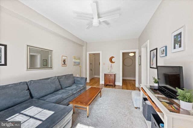 living room featuring baseboards, ceiling fan, and wood finished floors