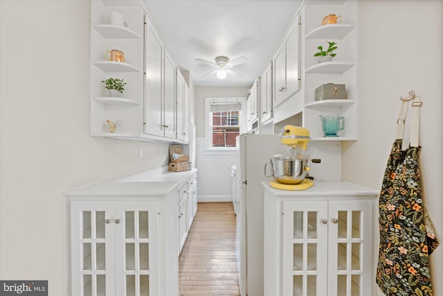 interior space featuring open shelves, white cabinets, a ceiling fan, and light wood-style floors