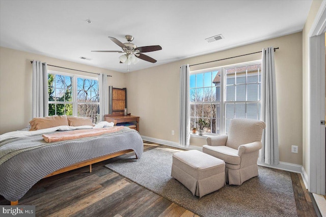 bedroom featuring ceiling fan, visible vents, baseboards, and wood finished floors