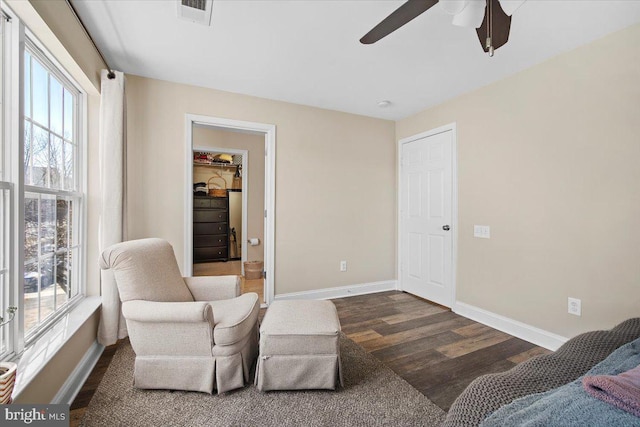 sitting room with a ceiling fan, wood finished floors, visible vents, and baseboards