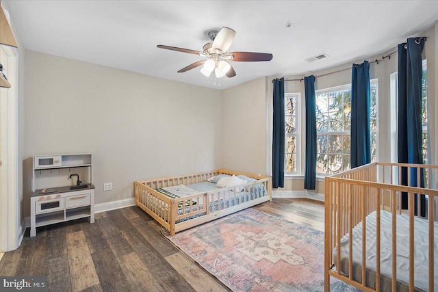 bedroom with visible vents, baseboards, wood finished floors, and a ceiling fan