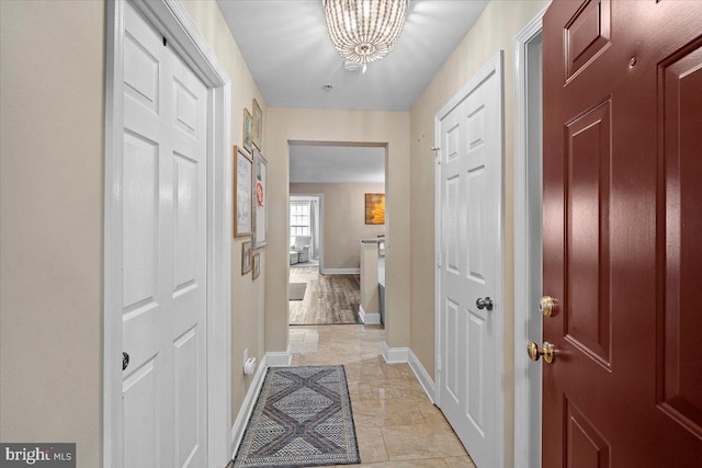 hall with baseboards and a chandelier