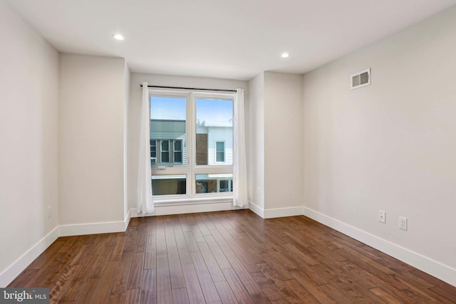 unfurnished room with visible vents, recessed lighting, dark wood-type flooring, and baseboards