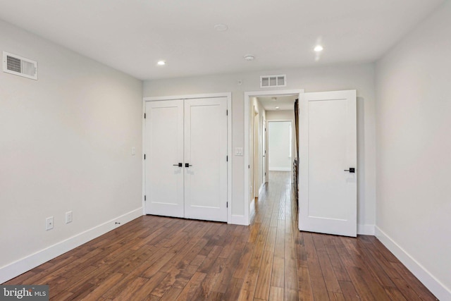 unfurnished bedroom with a closet, baseboards, visible vents, and dark wood-style flooring