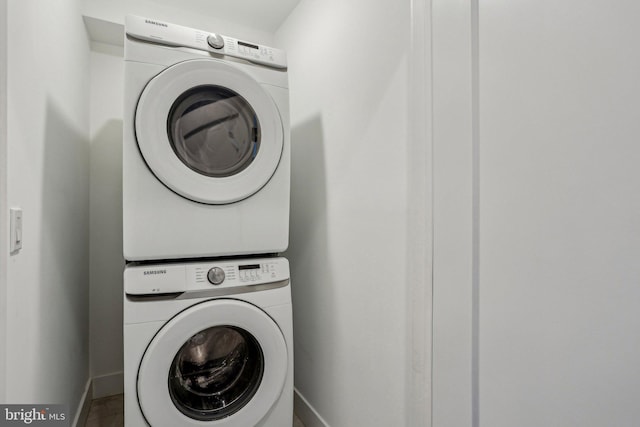 laundry room featuring baseboards, laundry area, and stacked washer / dryer