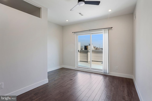 empty room featuring dark wood finished floors, visible vents, and baseboards