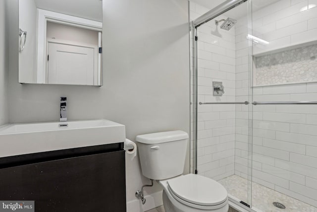 bathroom with a stall shower, toilet, vanity, and baseboards