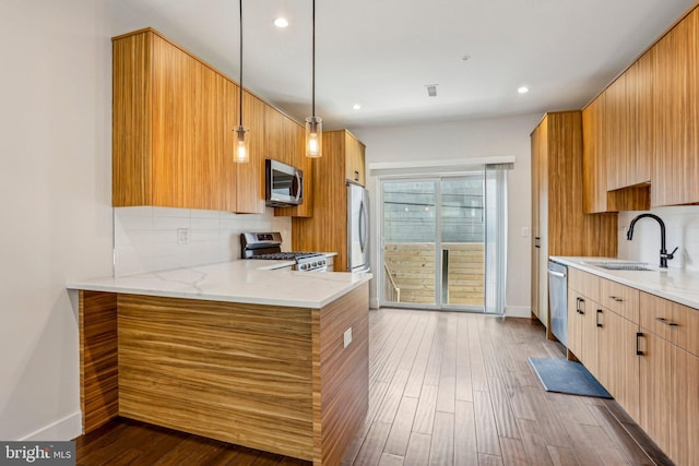 kitchen with dark wood finished floors, decorative backsplash, appliances with stainless steel finishes, and a sink