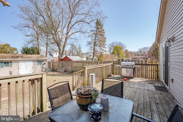 deck with a fenced backyard, a grill, outdoor dining area, and an outdoor structure