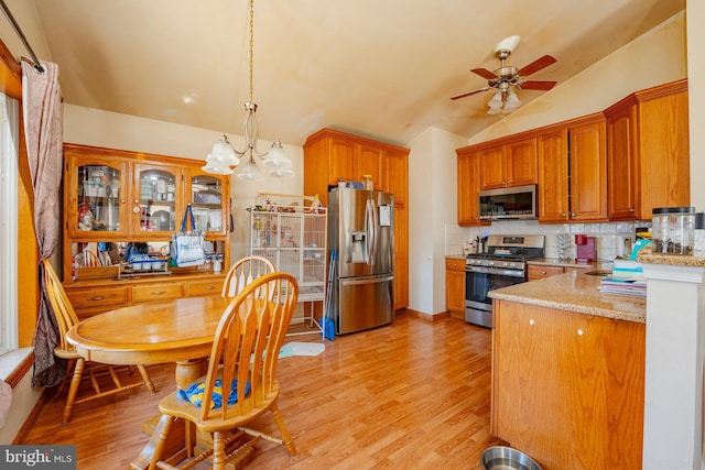 kitchen featuring tasteful backsplash, appliances with stainless steel finishes, light wood-style floors, and vaulted ceiling