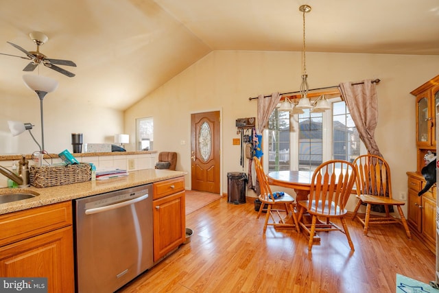 kitchen featuring brown cabinetry, light stone countertops, lofted ceiling, stainless steel dishwasher, and light wood-type flooring