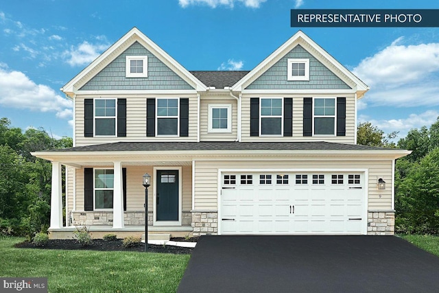 craftsman-style house with a porch, a front yard, a garage, stone siding, and driveway