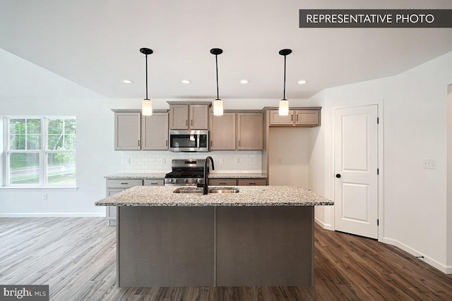 kitchen featuring a sink, backsplash, appliances with stainless steel finishes, and dark wood-style floors