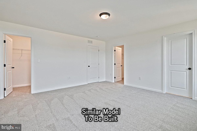 unfurnished bedroom featuring carpet flooring, a walk in closet, and baseboards