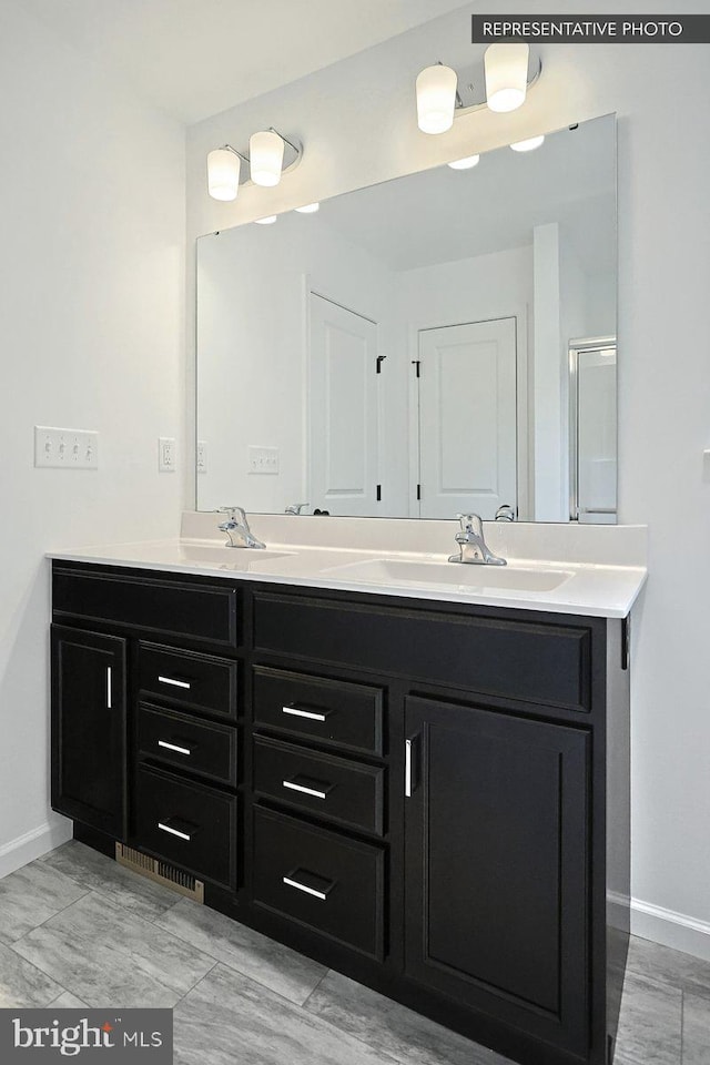 bathroom with a sink, baseboards, and double vanity