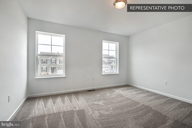 carpeted spare room featuring visible vents and baseboards