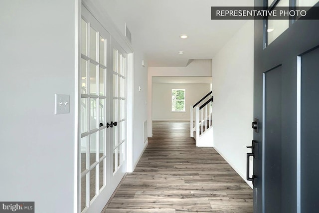 foyer entrance featuring stairs, wood finished floors, baseboards, and french doors