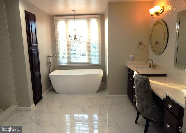 bathroom featuring a notable chandelier, marble finish floor, baseboards, a freestanding bath, and vanity