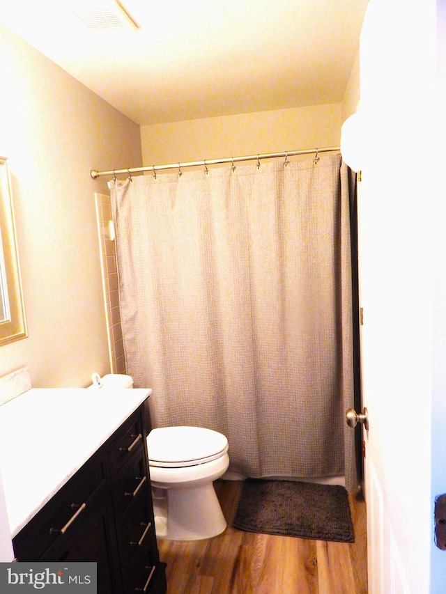 bathroom with visible vents, toilet, a shower with curtain, wood finished floors, and vanity