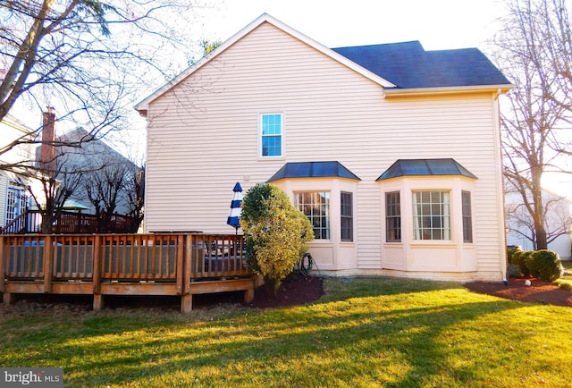 rear view of house with a deck and a yard