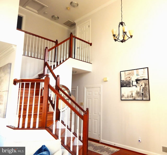 staircase featuring crown molding, baseboards, visible vents, and a towering ceiling