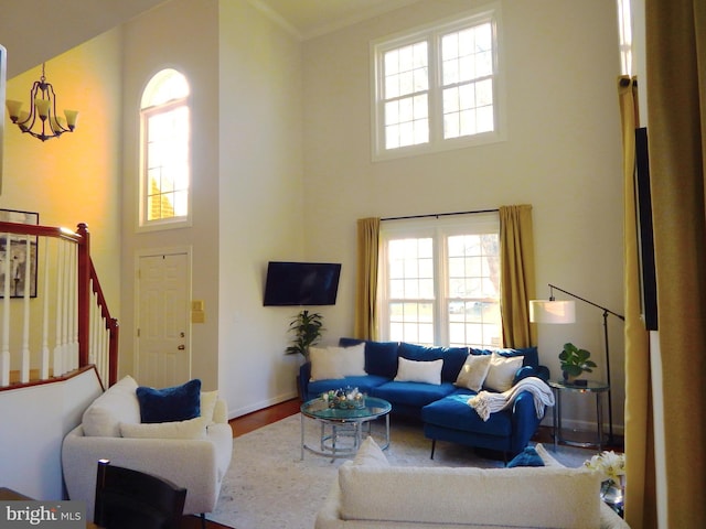 living room featuring a high ceiling, an inviting chandelier, wood finished floors, and stairs