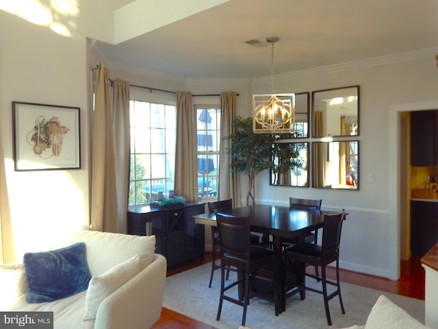 dining space with a chandelier, crown molding, and wood finished floors