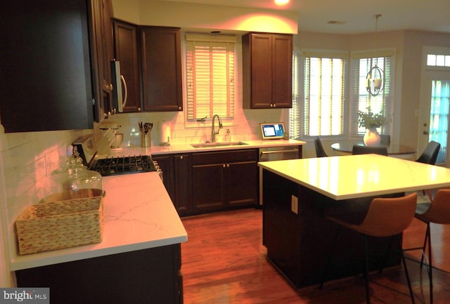 kitchen featuring tasteful backsplash, a breakfast bar, range with gas stovetop, dark wood-style floors, and a sink